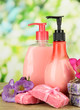 Liquid and hand-made soaps on wooden table, on green background