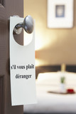 Photo: Sign with French text "s'il vous plait deranger" (please disturb) hanging on hotel room door Sign with French text "s'il vous plait deranger" (please disturb) hanging on hotel room door