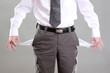 Business man showing his empty pockets, on grey background