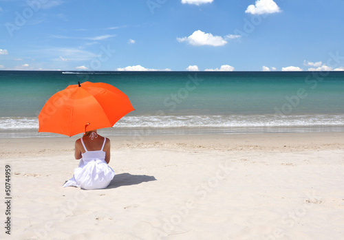 Photo: Girl with an orange umbrella on the sandy beach Girl with an orange umbrella on the sandy beach