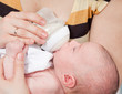 Foto: Mother feeds the baby with milk from a children's small bottle Mother feeds the baby with milk from a children's small bottle