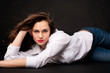 Photo: Portrait of beautiful young woman in jeans and shirt lying and l Portrait of beautiful young woman in jeans and shirt lying and l