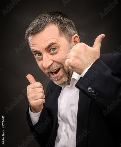 Photo: Successful man shows ok sigh on dark background Successful man shows ok sigh on dark background
