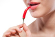 Photo: Young woman with chili pepper isolated on white Young woman with chili pepper isolated on white