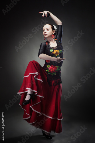 Photo: young woman dancing flamenco with castanets on black young woman dancing flamenco with castanets on black