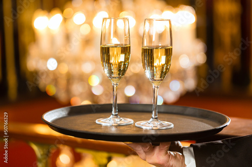 Photo: Waiter served champagne glasses on tray in restaurant Waiter served champagne glasses on tray in restaurant