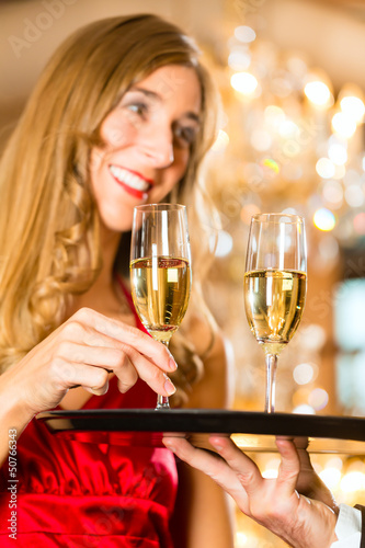 Photo: Waiter serves champagne glasses on tray in restaurant Waiter serves champagne glasses on tray in restaurant