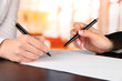 Foto: Two business partners signing document, on bright background Two business partners signing document, on bright background
