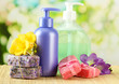 Liquid and hand-made soaps on wooden table, on green background