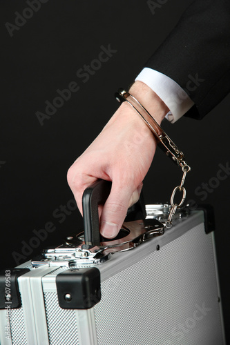 Photo: Hand with handcuff and suitcase, isolated on black Hand with handcuff and suitcase, isolated on black