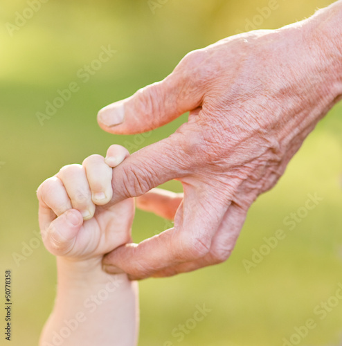 Photo: old man and a kid holding hands together old man and a kid holding hands together