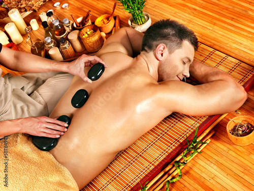 Photo: Man getting stone therapy massage . Man getting stone therapy massage .