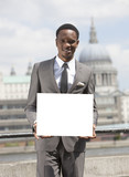 Photo: Portrait of African American businessman smiling and holding blank cardboard Portrait of African American businessman smiling and holding blank cardboard