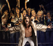 Photo: Portrait of young man in fur coat screaming with excited audience in the background Portrait of young man in fur coat screaming with excited audience in the background