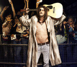 Photo: Portrait of young rock musician with guitar posing for excited audience at concert Portrait of young rock musician with guitar posing for excited audience at concert