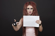 Photo: Portrait of arrogant young funky woman pointing towards blank placard against black background Portrait of arrogant young funky woman pointing towards blank placard against black background