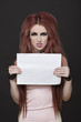Photo: Portrait of arrogant young funky woman with blank placard standing against black background Portrait of arrogant young funky woman with blank placard standing against black background