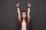 Photo: Portrait of funky young woman sticking out tongue and making rebellious gestures over black background Portrait of funky young woman sticking out tongue and making rebellious gestures over black background