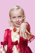 Foto: Portrait of a happy young girl dressed in princess costume displaying ring over pink background Portrait of a happy young girl dressed in princess costume displaying ring over pink background