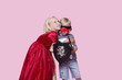 Foto: Happy young girl in princess costume hugging boy pretending to be her hero over pink background Happy young girl in princess costume hugging boy pretending to be her hero over pink background