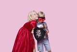 Foto: Happy young girl in princess costume hugging boy pretending to be her hero over pink background Happy young girl in princess costume hugging boy pretending to be her hero over pink background