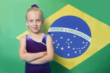 Photo: Portrait of a happy young female gymnast with arms crossed standing in front of Brazilian flag Portrait of a happy young female gymnast with arms crossed standing in front of Brazilian flag