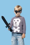 Photo: Portrait of a young boy in pirate costume holding sword over blue background Portrait of a young boy in pirate costume holding sword over blue background