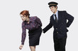 Foto: Portrait of young pilot touching flight attendant inappropriately against gray background Portrait of young pilot touching flight attendant inappropriately against gray background