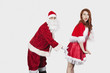 Foto: Portrait of Santa touching Mrs. Santa inappropriately against gray background Portrait of Santa touching Mrs. Santa inappropriately against gray background