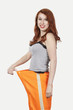 Photo: Portrait of young Caucasian woman oversized orange pants against gray background Portrait of young Caucasian woman oversized orange pants against gray background