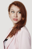Photo: Beautiful young businesswoman in pink suit looking away against gray background Beautiful young businesswoman in pink suit looking away against gray background