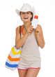 Smiling young beach woman in hat holding sun screen creme