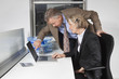 Photo: Side view of businesswoman and man looking at laptop screen at desk in office Side view of businesswoman and man looking at laptop screen at desk in office