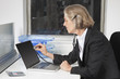Photo: Side view of senior businesswoman examining laptop with the use of stethoscope at office desk Side view of senior businesswoman examining laptop with the use of stethoscope at office desk