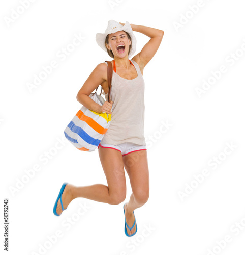 Photo: Happy young beach woman in hat jumping Happy young beach woman in hat jumping