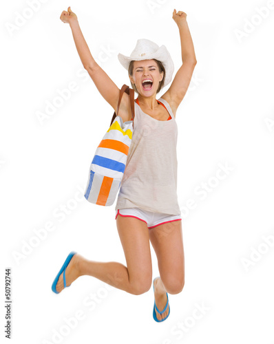 Photo: Smiling young beach woman in hat jumping Smiling young beach woman in hat jumping