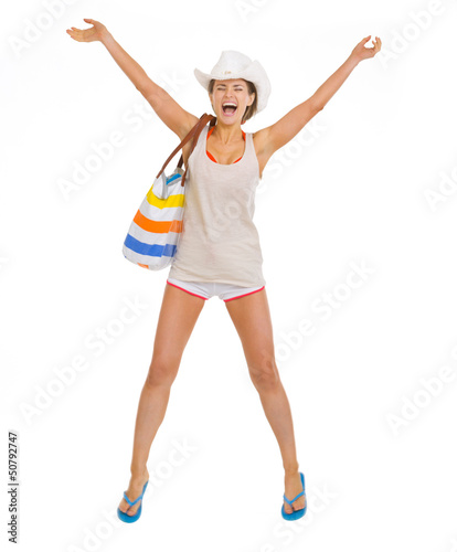 Photo: Happy young beach woman in hat jumping Happy young beach woman in hat jumping