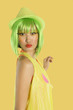 Photo: Portrait of funky young woman with green hair puckering her lips against yellow background Portrait of funky young woman with green hair puckering her lips against yellow background