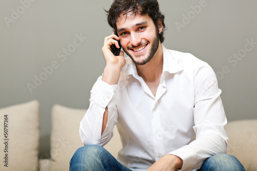 Photo: Relaxed young guy enjoying conversation on the sofa Relaxed young guy enjoying conversation on the sofa