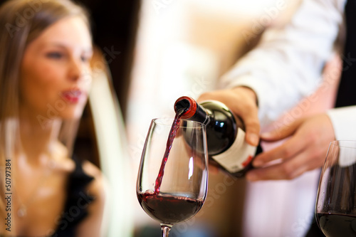 Photo: Waiter pouring red wine to a woman Waiter pouring red wine to a woman
