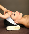 Beautiful young woman in spa salon taking head massage,