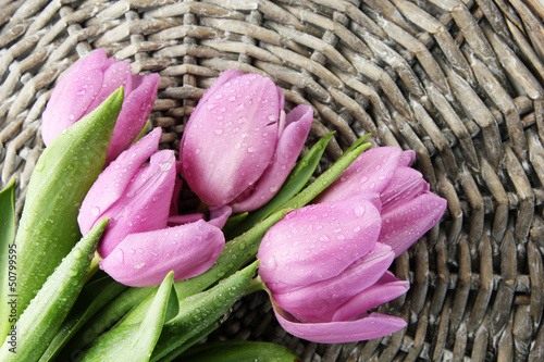 Photo: Beautiful bouquet of purple tulips, on grey wicker background Beautiful bouquet of purple tulips, on grey wicker background