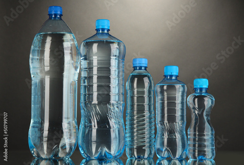 Photo: Different water bottles on grey background Different water bottles on grey background