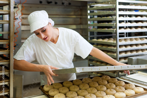 Photo: Female baker baking bread rolls Female baker baking bread rolls