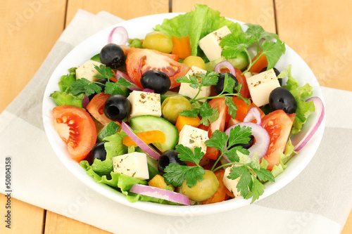Photo: Fresh salad in plate on wooden table Fresh salad in plate on wooden table