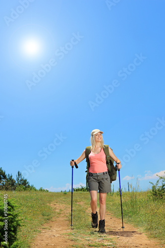Photo: Young woman with backpack walking at sunny day in the mountain Young woman with backpack walking at sunny day in the mountain