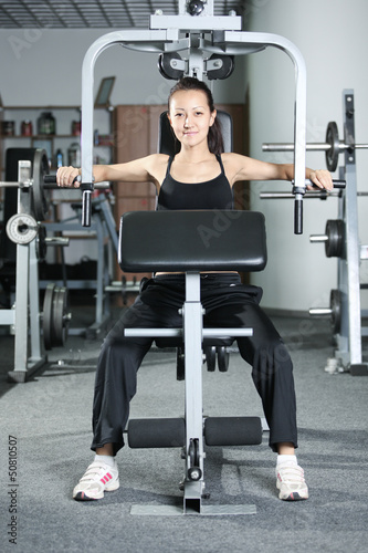Photo: The girl is engaged in gym doing exercise strengthens chest The girl is engaged in gym doing exercise strengthens chest