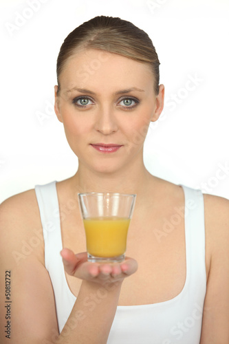 Photo: blonde woman showing a glass of orange juice blonde woman showing a glass of orange juice