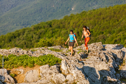 Photo: Two women is trekking in the Crimea mountains with backpacks Two women is trekking in the Crimea mountains with backpacks
