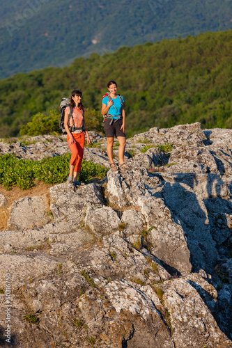 Photo: Two women is trekking in the Crimea mountains with backpacks Two women is trekking in the Crimea mountains with backpacks